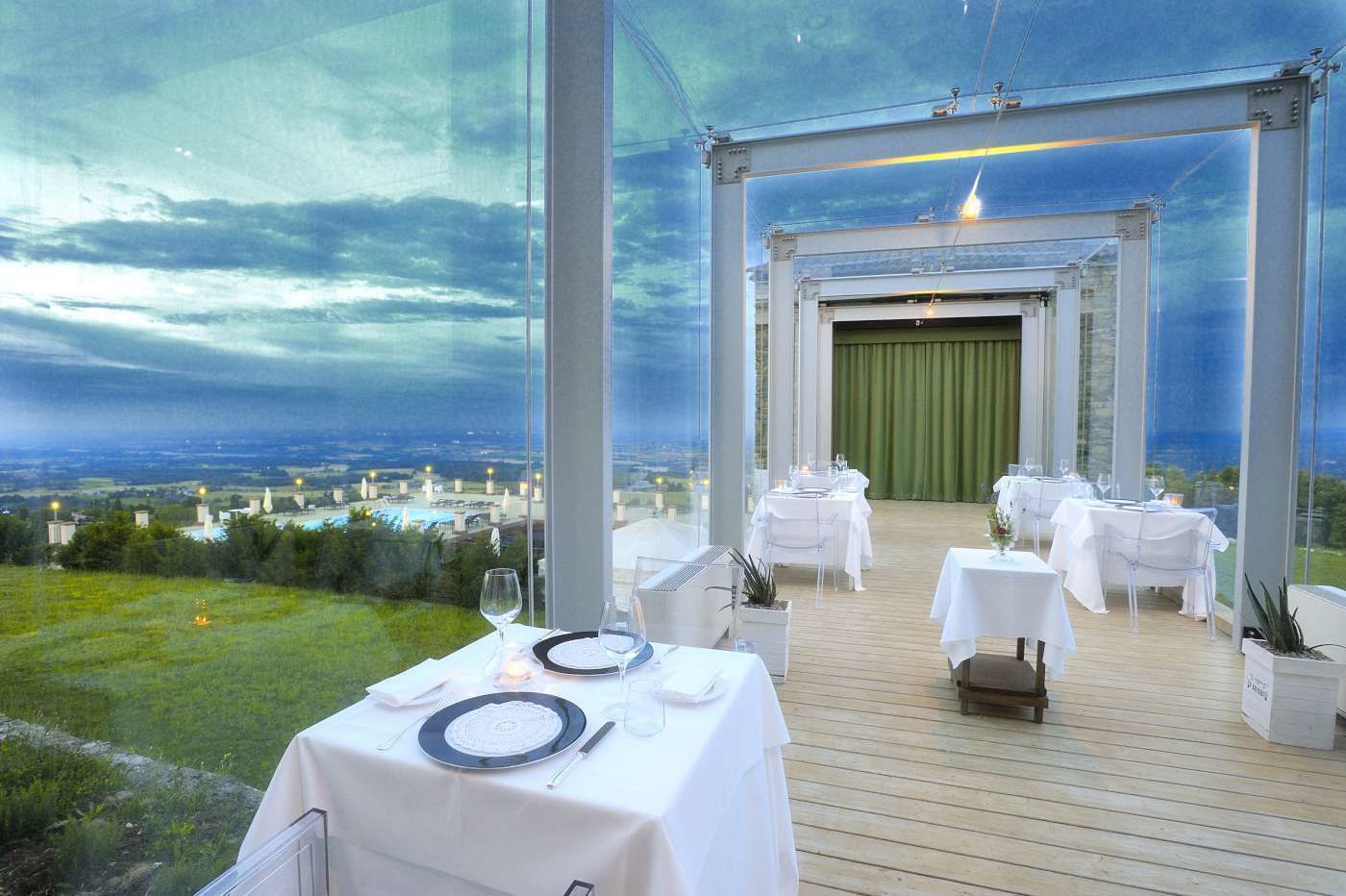 An outdoor dining area with tables set for a meal, overlooking a cityscape.