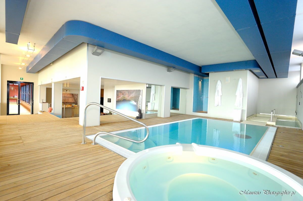 A pool area with a hot tub, wooden deck, and a view of the ship's interior.
