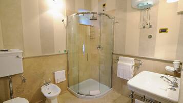 A modern bathroom with a glass-enclosed shower, a bidet, a sink, and a toilet.