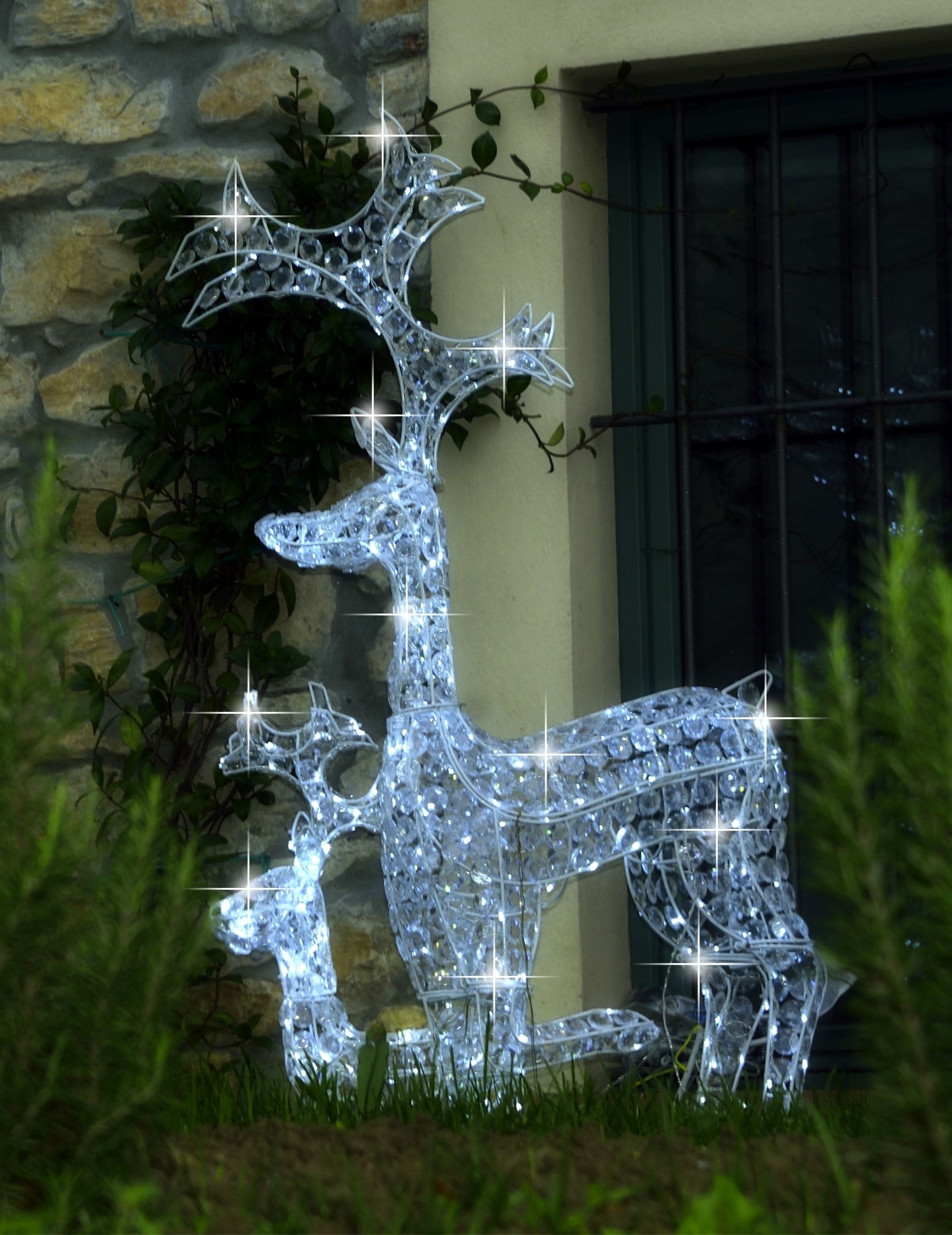 A decorative glass reindeer sculpture in front of a stone wall and a window.