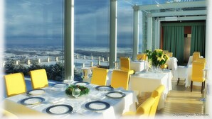 Un restaurant où les tables sont dressées pour le service, avec de grandes fenêtres donnant sur un paysage enneigé.