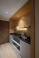 Una cocina moderna con muebles de madera, encimera negra e iluminación empotrada.