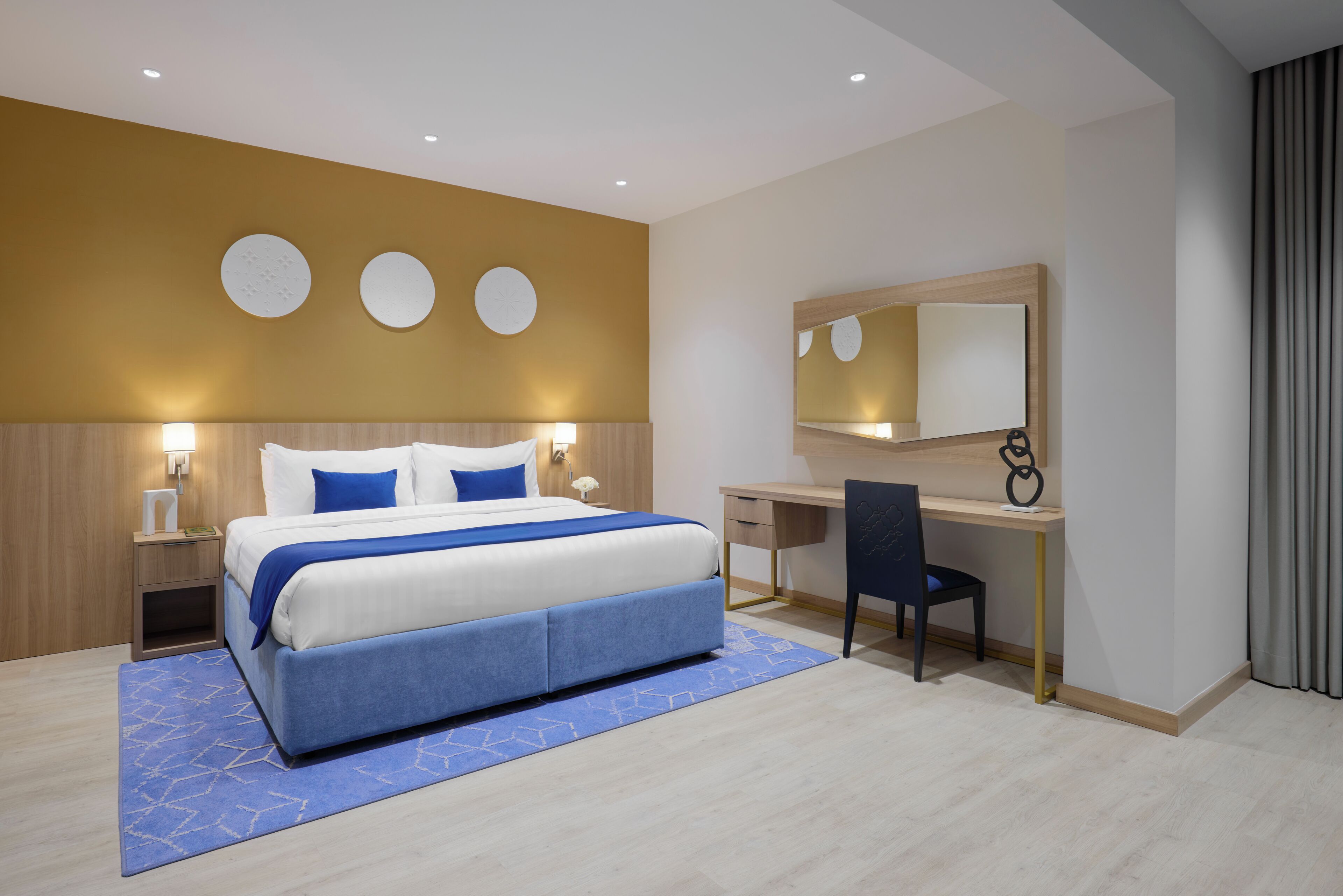 Ein modernes Hotelzimmer mit einem großen Bett, einem Schreibtisch und einem Spiegel.