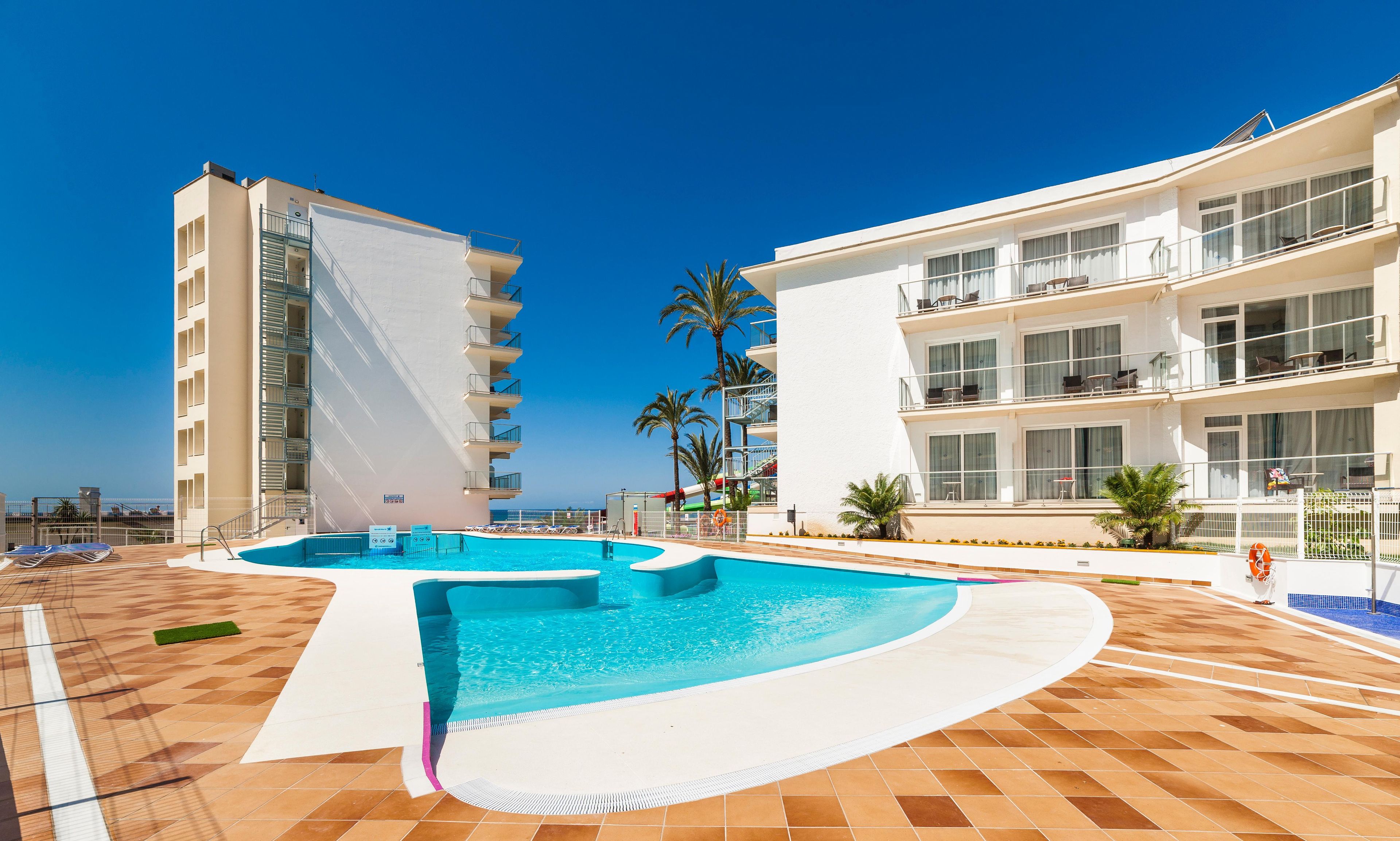 A swimming pool with a curved design, surrounded by a tiled deck.