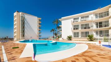 A swimming pool with a curved design, surrounded by a tiled deck.