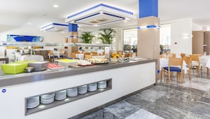 A modern buffet area with a variety of food options, including fruits and desserts, and a seating area with tables and chairs. - Globales Playa Estepona (Estepona)