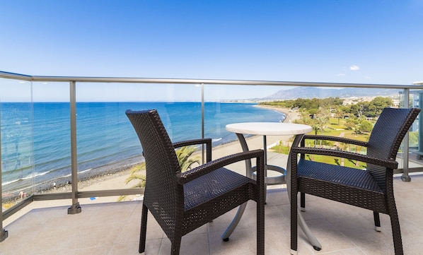 A balcony with two wicker chairs and a small table, overlooking a beach and ocean. - Globales Playa Estepona (Estepona)
