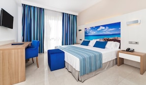 Una habitación de hotel con cama, escritorio, silla, teléfono y televisor.