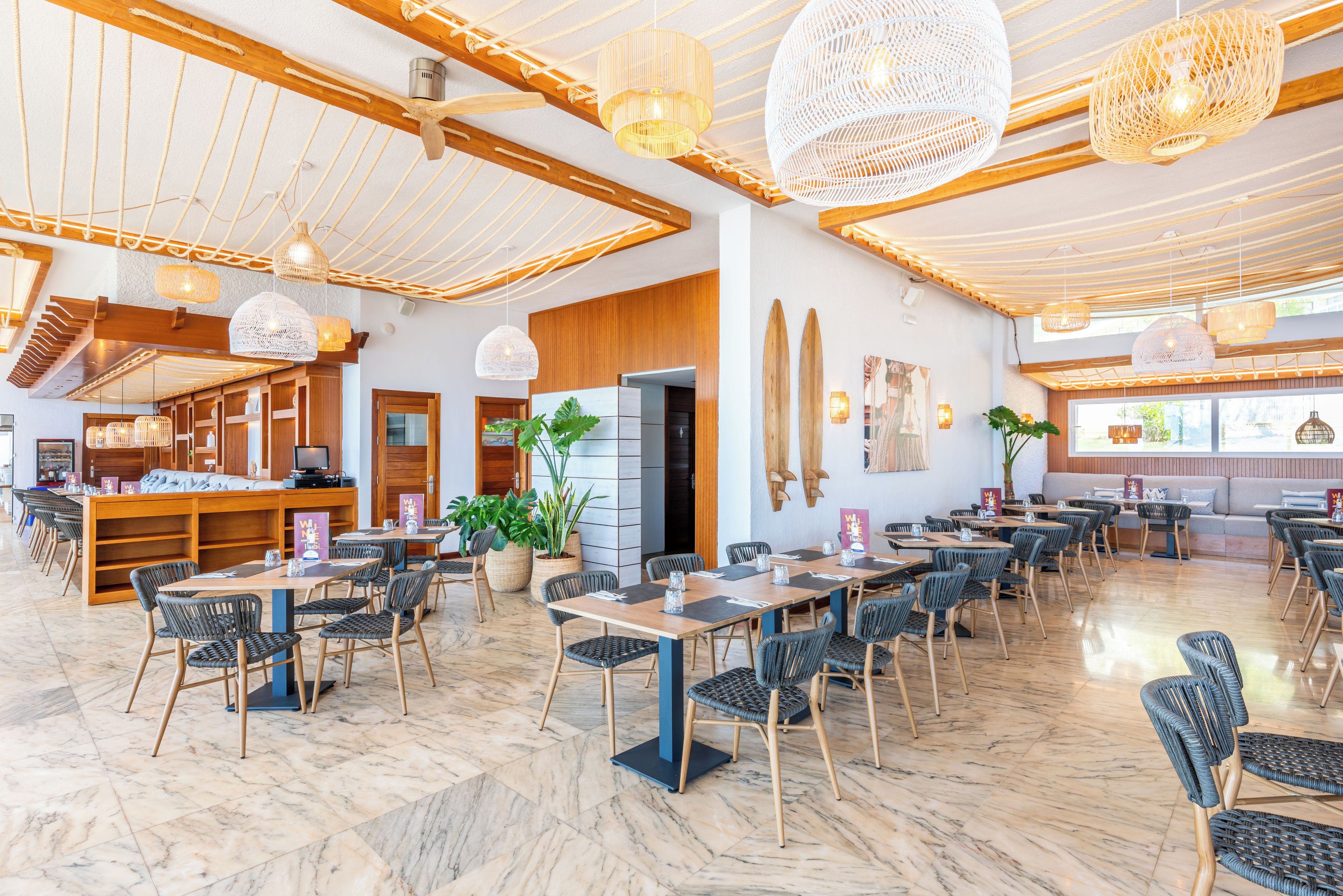 A spacious indoor area with multiple seating arrangements, including tables and chairs, and a variety of hanging light fixtures.