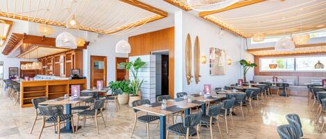 A spacious indoor area with multiple seating arrangements, including tables and chairs, and a variety of hanging light fixtures.