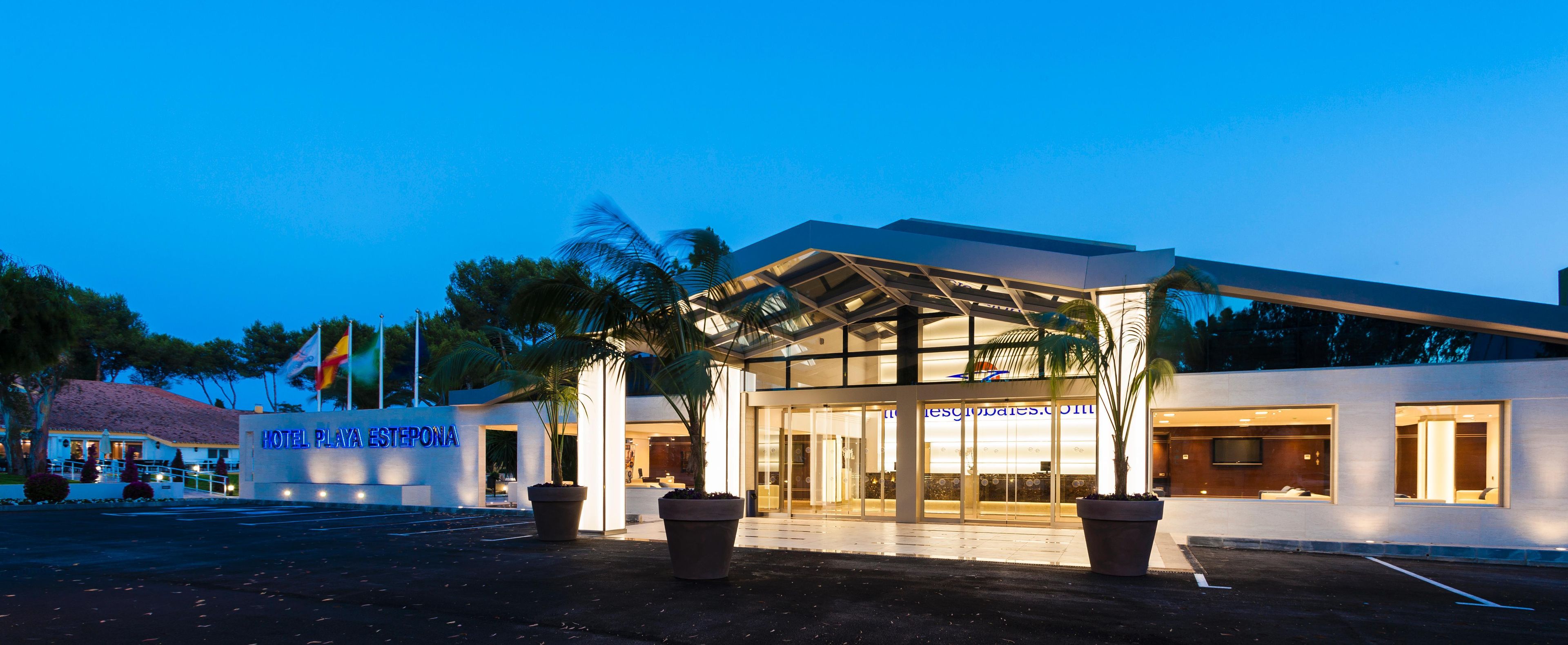 A hotel entrance with a covered walkway, large potted plants, and a visible sign for HOTEL PLAYA ESTEPONA.