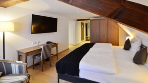 Un dormitorio con cama, escritorio, silla, televisor y armario.