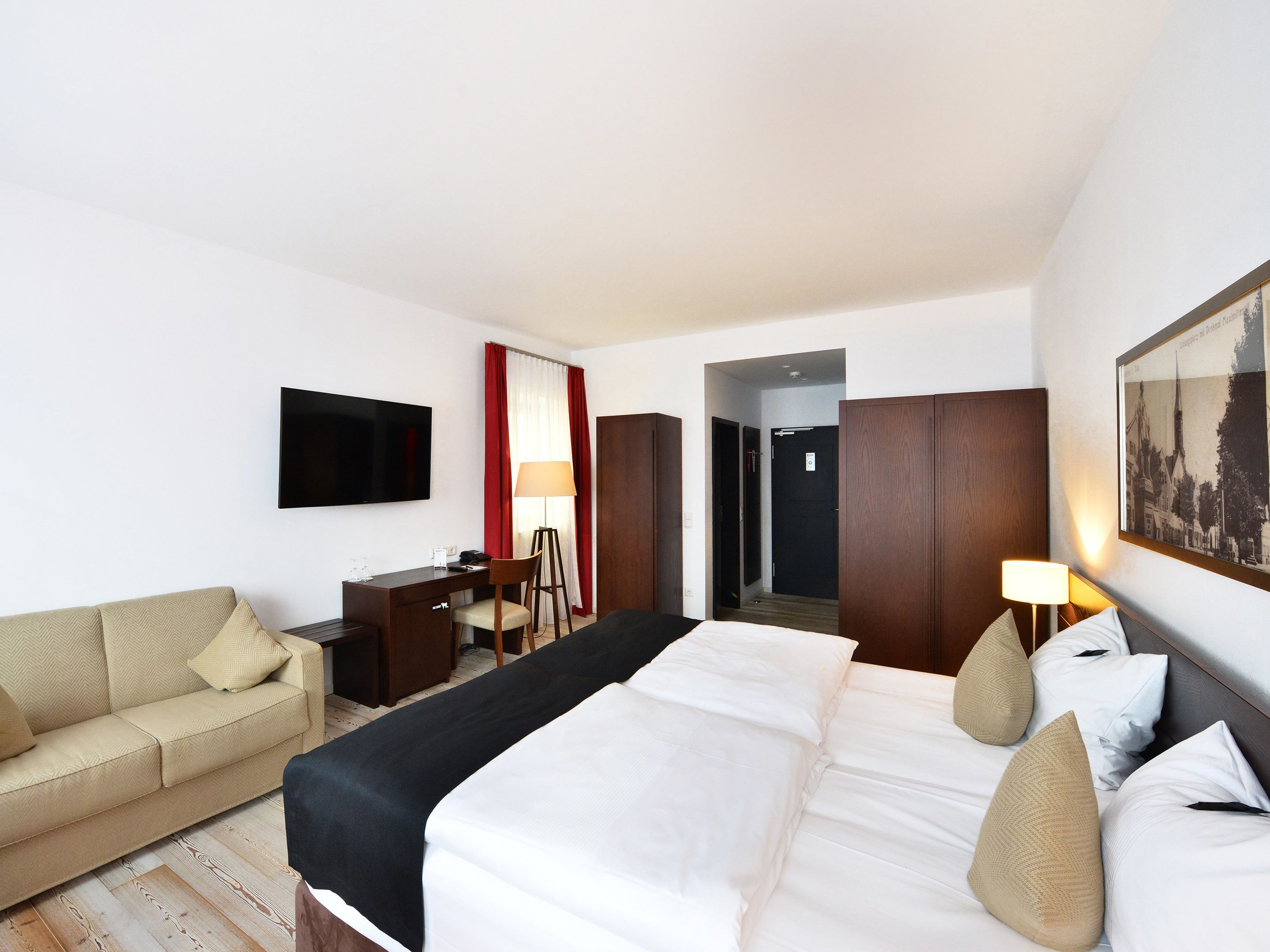 Una habitación de hotel con cama, escritorio, silla, televisor y armario.