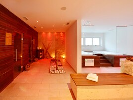 Um espaço de spa com um banco de madeira, uma mesa de massagem e uma parede de pedra.