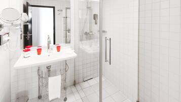 A modern bathroom with a white sink, mirror, and glass shower enclosure.