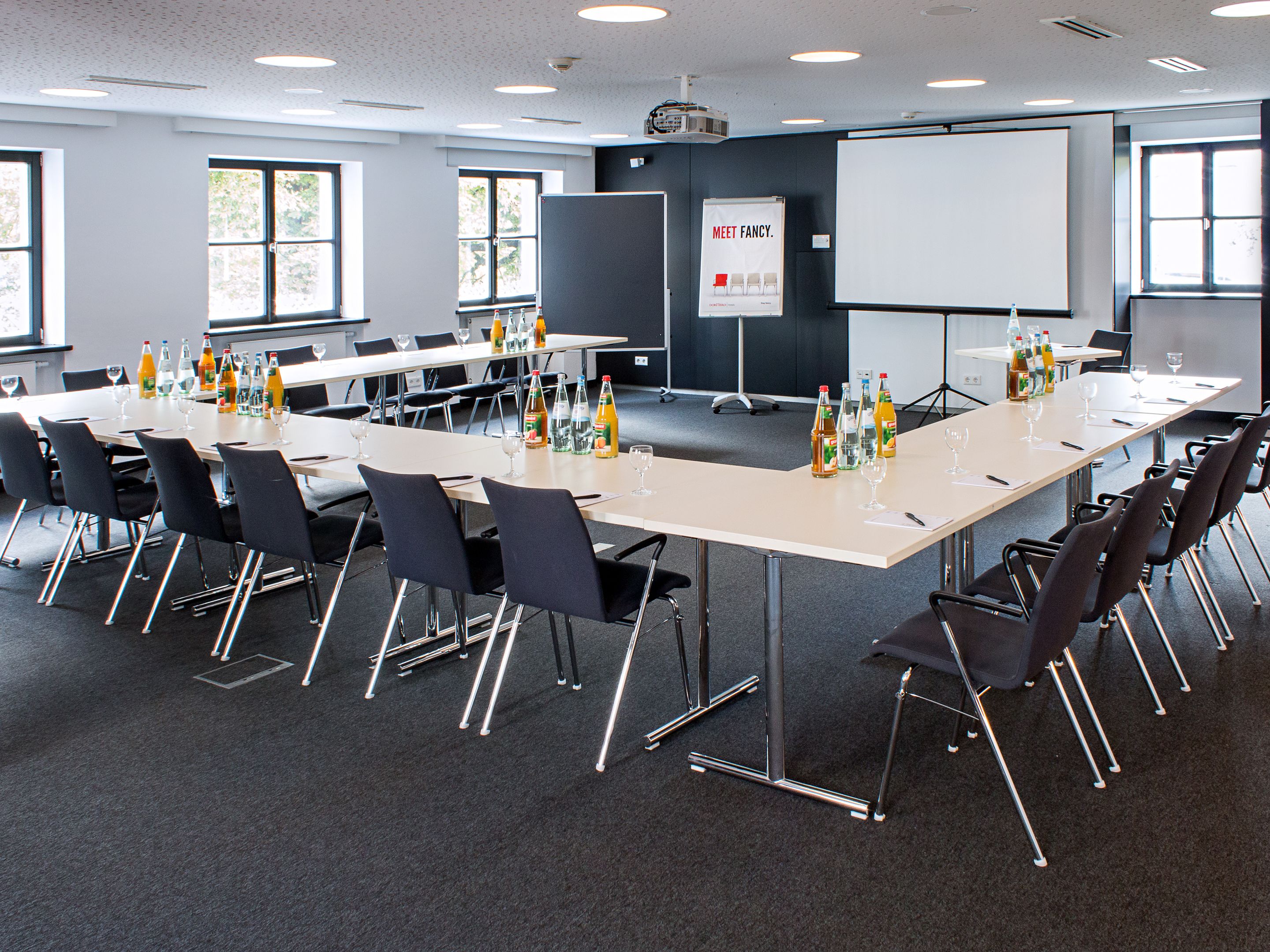 A conference room with a long table, chairs, and a projector screen.