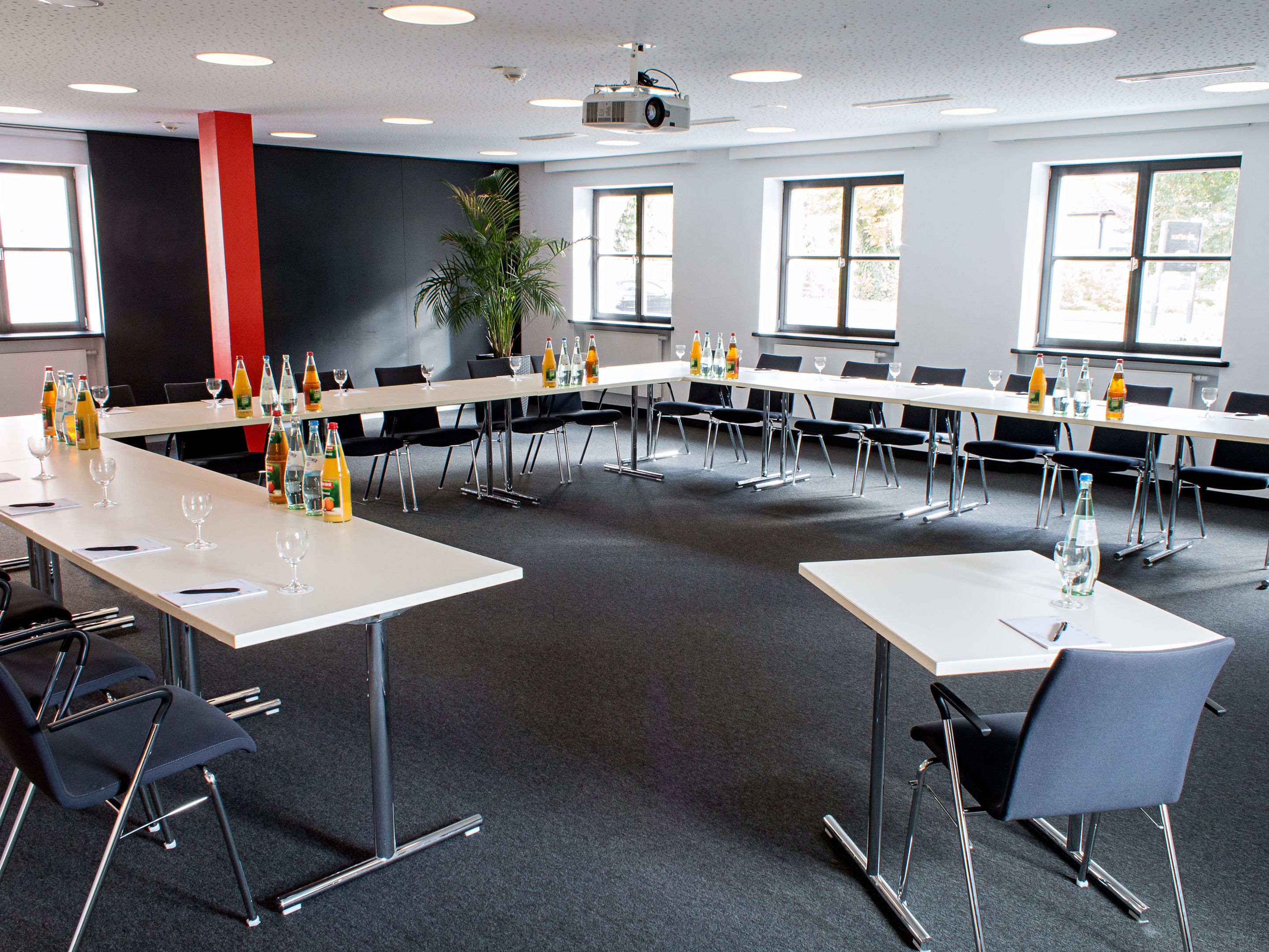 A conference room with multiple tables, chairs, and a projector screen.