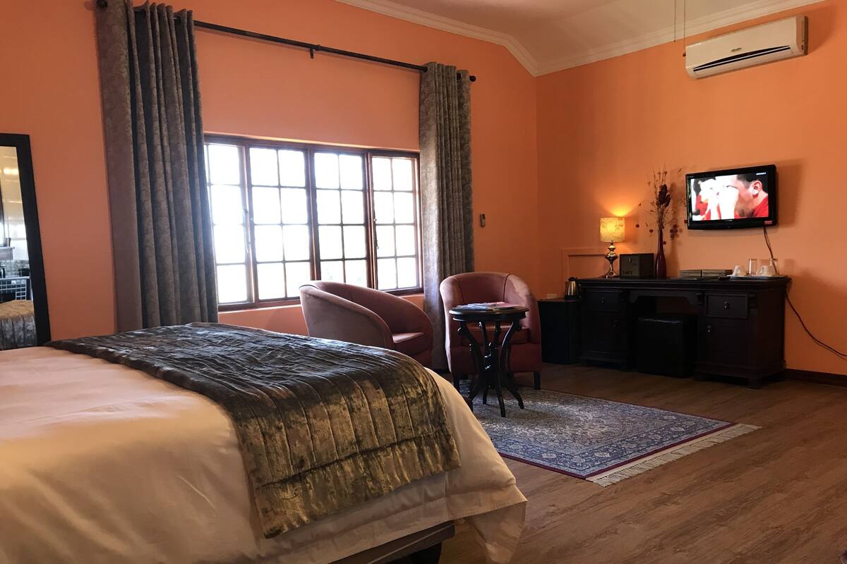 A hotel room with a bed, a desk, a chair, a television, and a window with curtains.