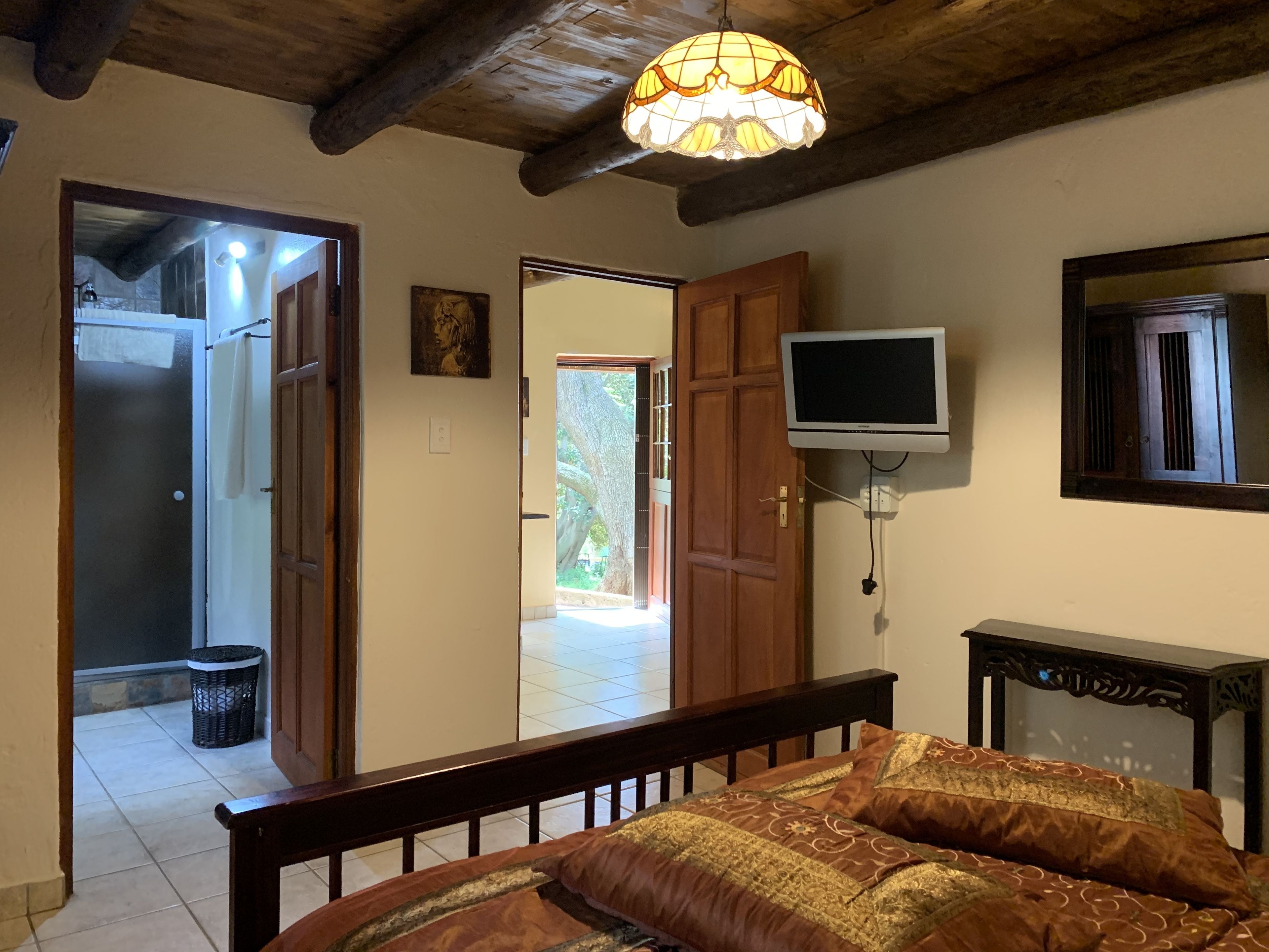 A bedroom with a bed, a television, and a large window.