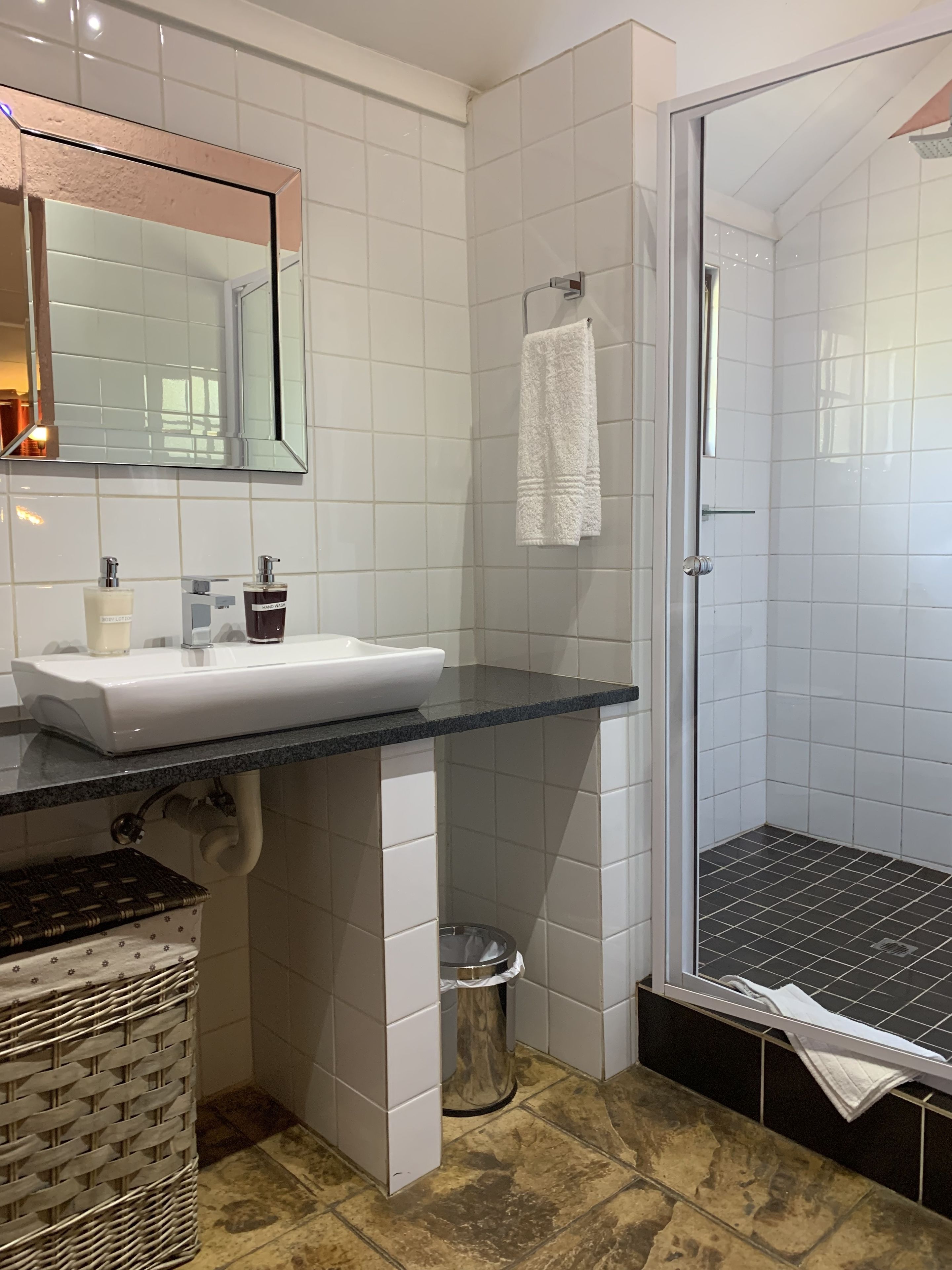 A modern bathroom with a white sink, mirror, and shower area.