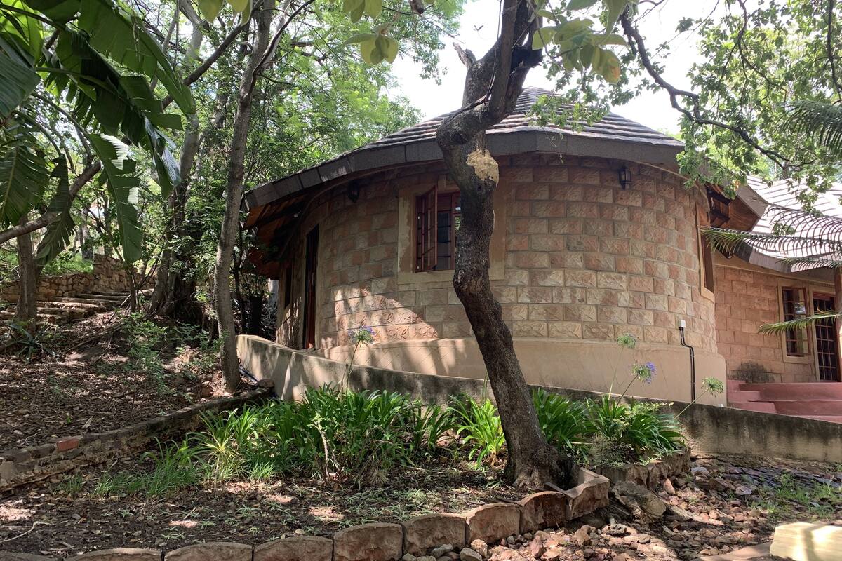 A stone building with a curved roof, surrounded by trees and a stone pathway.
