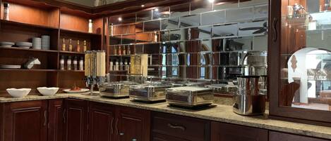 A kitchen with wooden cabinets, a marble countertop, and various kitchen appliances.