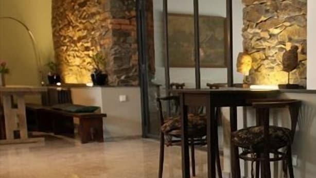 A dining area with a stone accent wall, a table with chairs, and a bench. - Alt Pension (Prague)