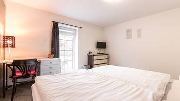 A bedroom with a bed, a desk, a chair, a dresser, and a television.