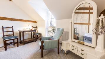 A bedroom with a skylight, a vanity with a mirror, a chair, and a dresser.