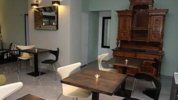 Uma sala de jantar com mesas, cadeiras, um armário de madeira e luminárias na parede.