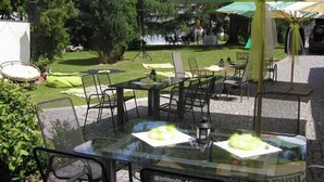 An outdoor patio area with tables and chairs, a large umbrella, and a lawn. - Alt Pension (Prague)