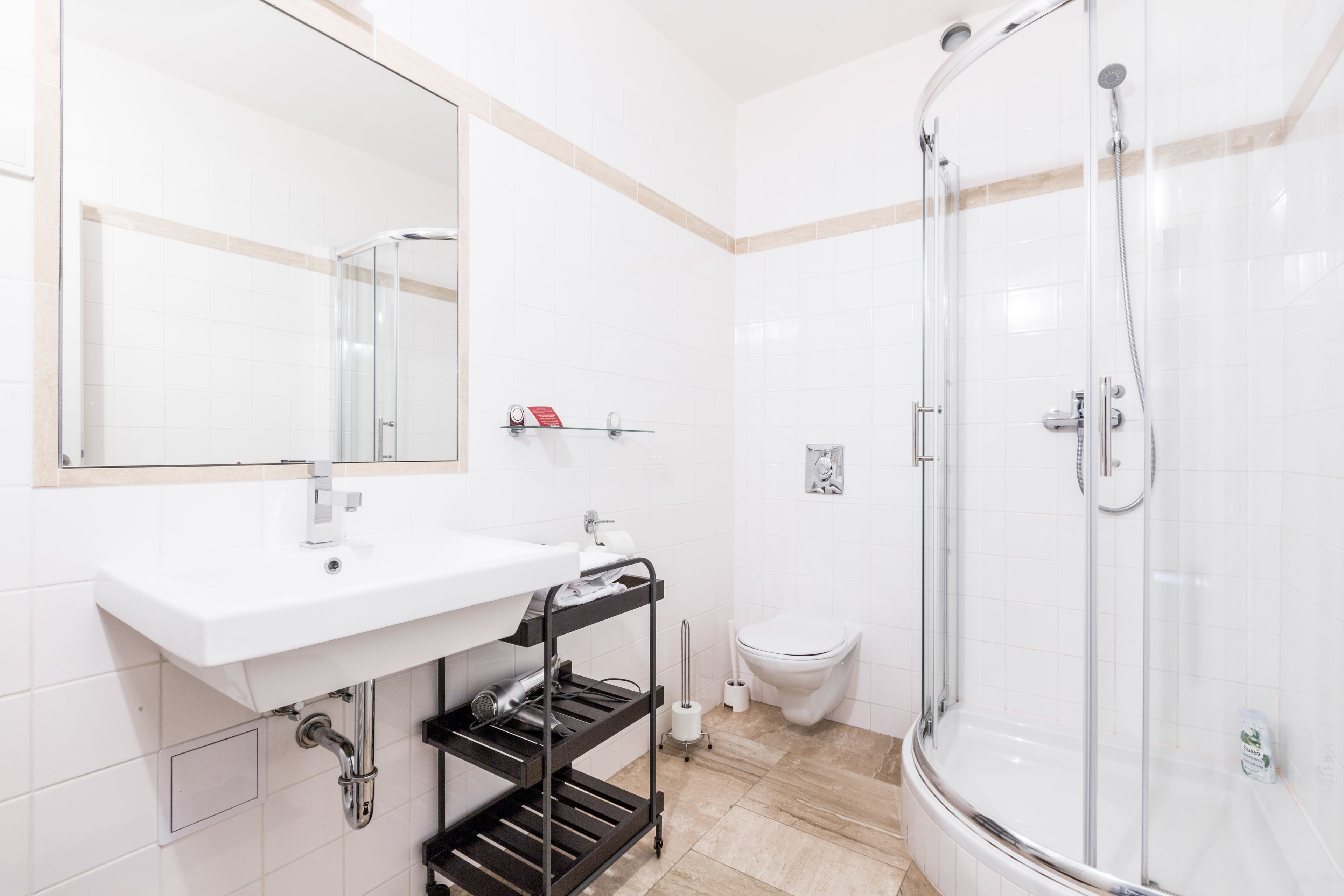 A modern bathroom with a white sink, mirror, and glass-enclosed shower.