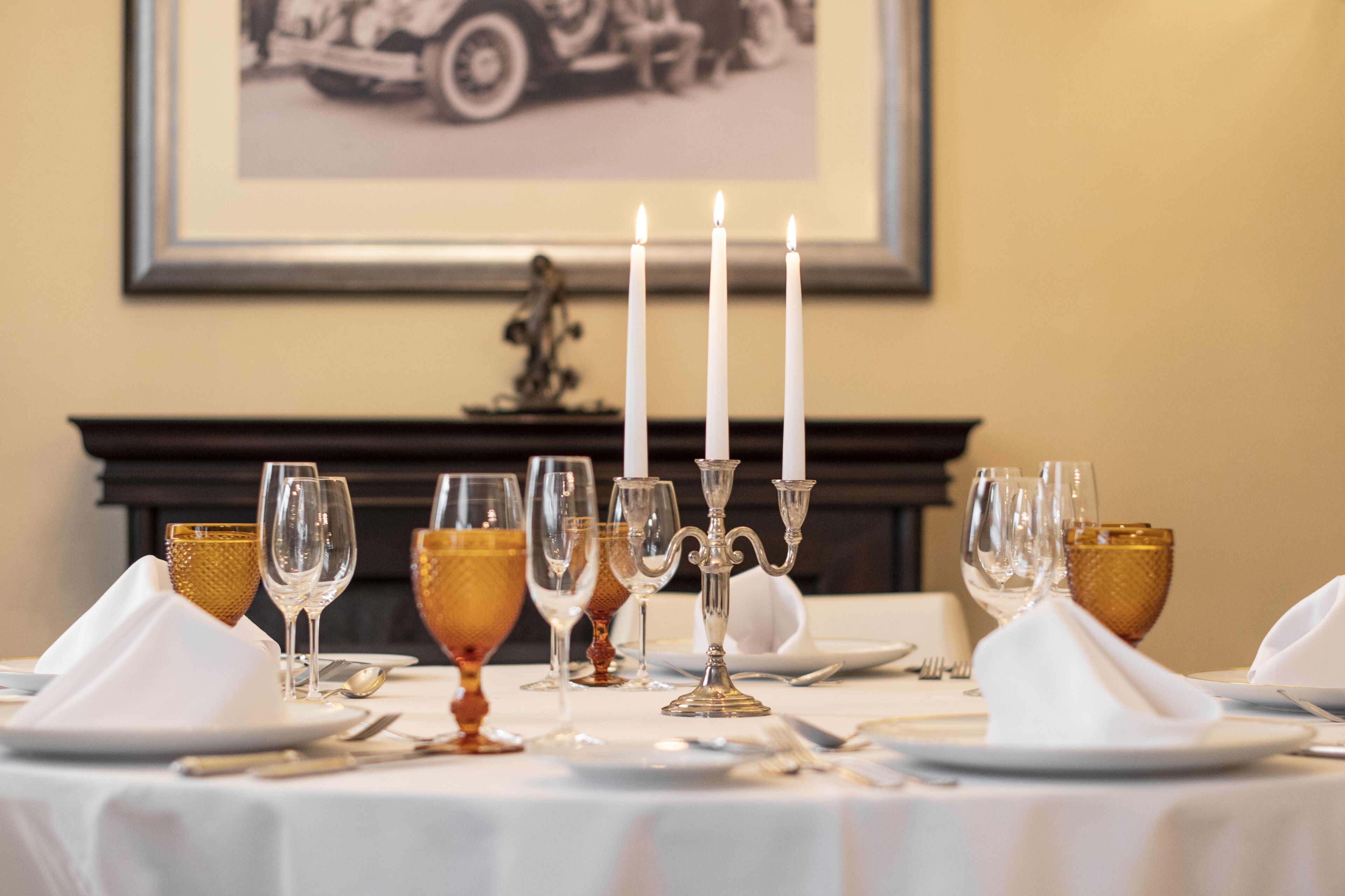 A table set for dining with white plates, clear wine glasses, and golden goblets.