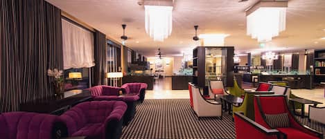 A hotel lobby with purple seating, a checkered floor, and a bar area.