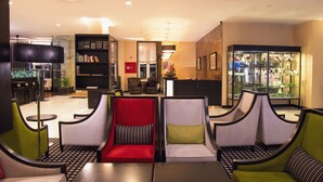En moderne lobby med receptionsdisk, siddeområde med stole og en bogreol.