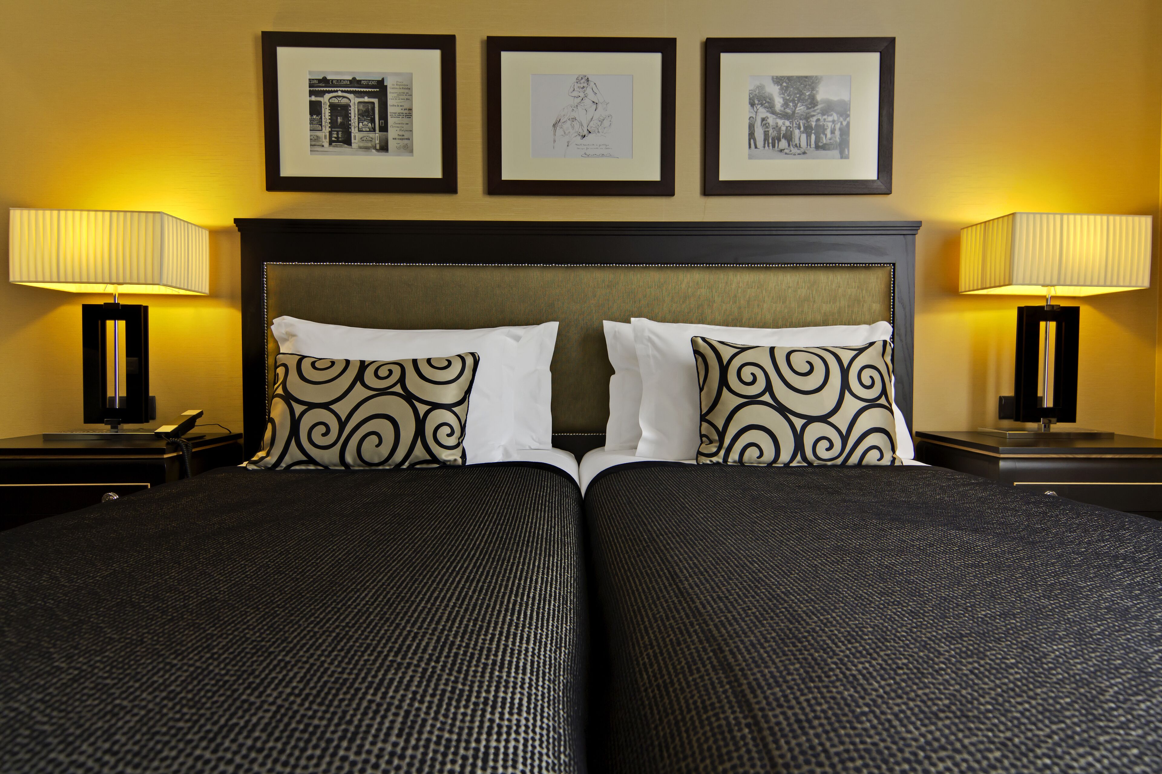 A double bed with a headboard, two bedside tables with lamps, and three framed pictures on the wall.