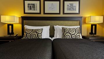 A double bed with a headboard, two bedside tables with lamps, and three framed pictures on the wall.