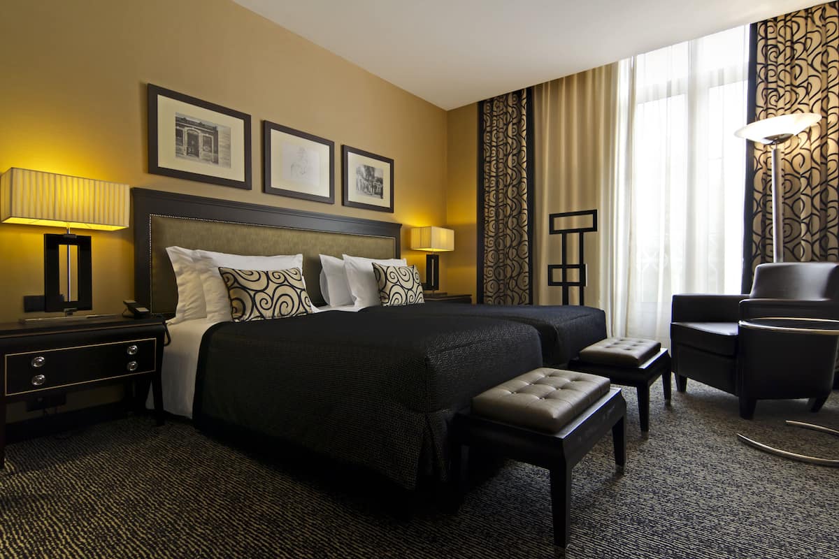 A hotel room with a large bed, two bedside tables, a chair, and a desk.