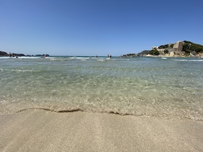 A beach with clear water, a sandy shore, and buildings in the background. - Hostal Villa Rosa (Calvia)