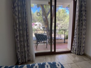 A room with a sliding glass door leading to an outdoor balcony with a table and chairs. - Hostal Villa Rosa (Calvia)