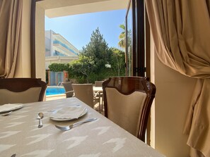 A dining area with a table set for two, overlooking a pool and greenery. - Hostal Villa Rosa (Calvia)