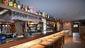Una zona de bar con una barra larga, taburetes y una variedad de botellas de licores.