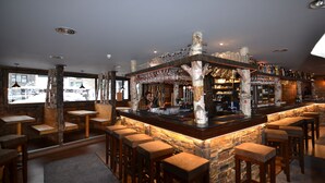 Zona de bar con taburetes de madera, mostrador de piedra y vistas al exterior a través de amplios ventanales.