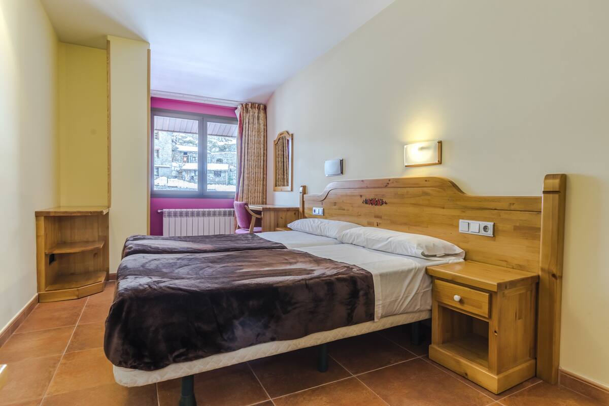 A bedroom with a bed, bedside table, and a window with curtains.