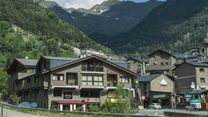 Una cabaña de montaña con varios pisos, un telesilla al fondo y un cartel de restaurante.