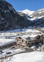 A snow-covered mountain town with a prominent building featuring a balcony and signage.