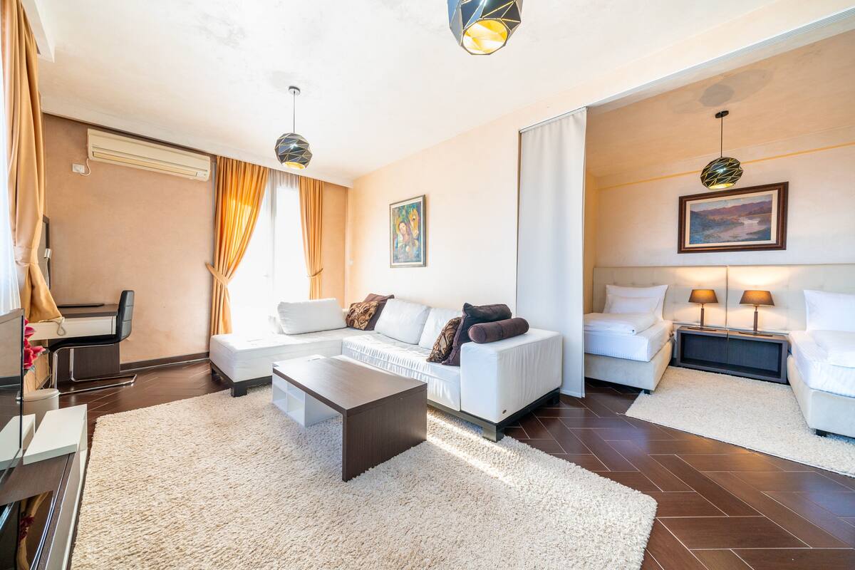 A modern living room with a sofa, coffee table, and two bedside tables with lamps.