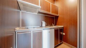 A compact kitchen with wooden cabinets, a built-in microwave, and a coffee maker.