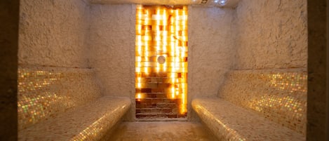 A sauna room with mosaic-tiled walls and benches.
