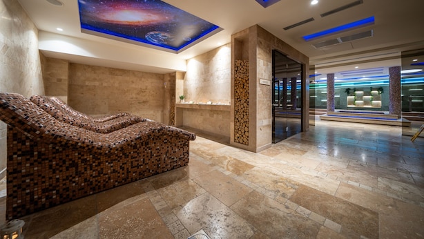 Ein moderner Wellnessbereich mit einer Mosaikbank, einer Decke mit einem Weltraum-Wandbild und einem gut beleuchteten Empfangsbereich.